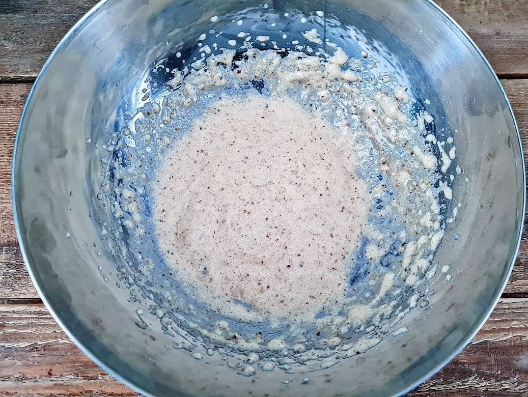 En metallskål med en blandning av smet som har en ljus färg och bubblor på ytan.